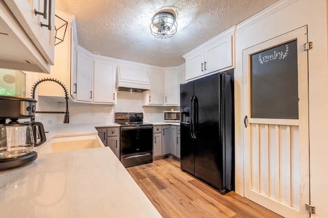 365 Quarles Ln, Ellijay, GA 30540 - kitchen featuring black fridge with ice dispenser, range with electric cooktop, premium range hood, light wood-style flooring, and light countertops