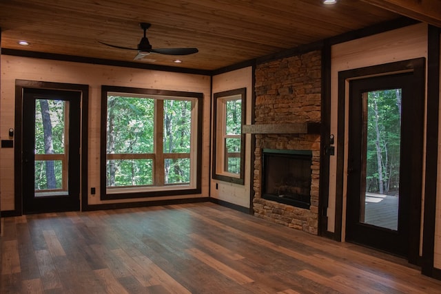 unfurnished living room featuring a fireplace, a healthy amount of sunlight, dark hardwood / wood-style floors, and wooden ceiling