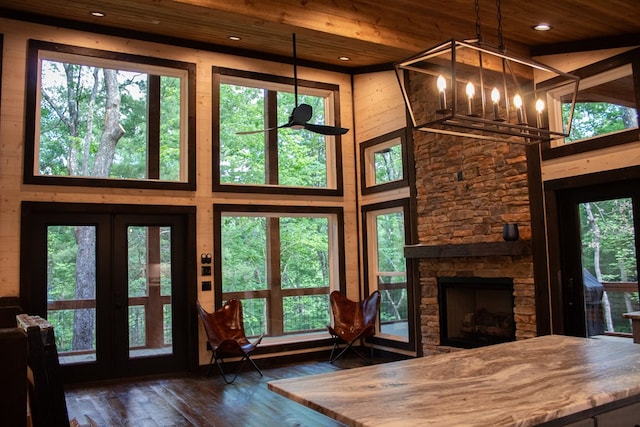 unfurnished living room featuring wood ceiling, dark hardwood / wood-style floors, a notable chandelier, a fireplace, and a high ceiling