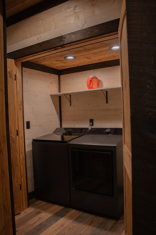 laundry room featuring hardwood / wood-style flooring, separate washer and dryer, and wood walls