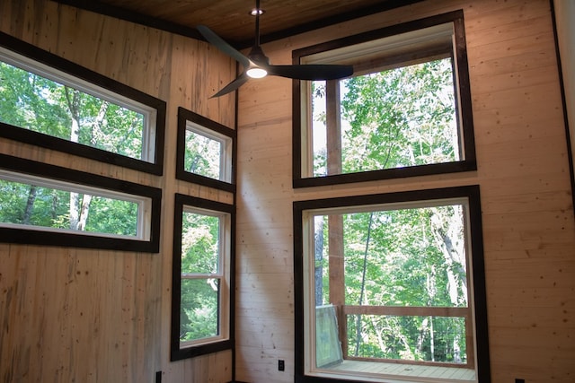 doorway to outside featuring a wealth of natural light, wooden walls, and ceiling fan