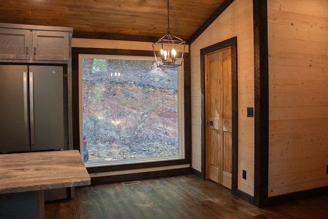 unfurnished dining area featuring a notable chandelier, dark wood-type flooring, and a healthy amount of sunlight