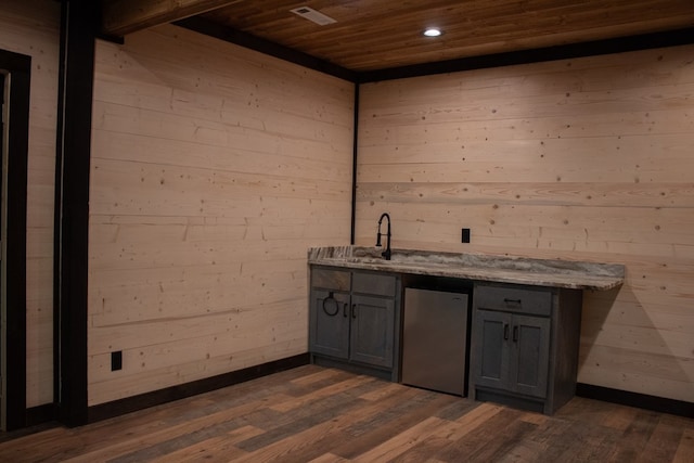 bar featuring dark hardwood / wood-style floors, refrigerator, gray cabinetry, light stone countertops, and wooden ceiling