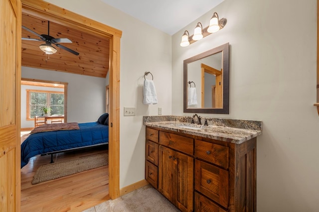 ensuite bathroom featuring baseboards, ceiling fan, ensuite bathroom, vaulted ceiling, and vanity