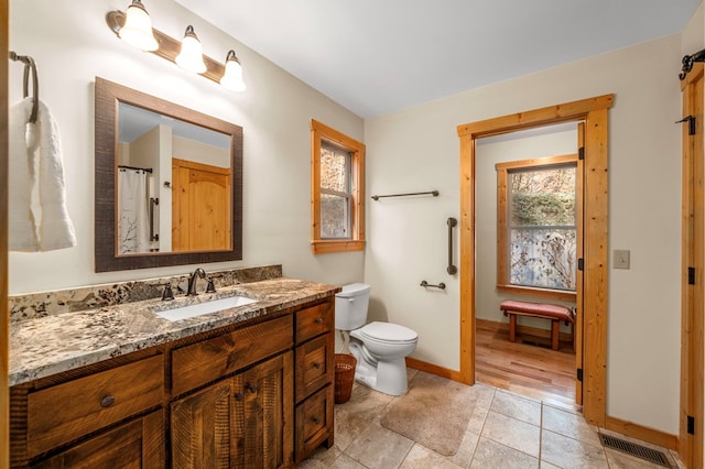 bathroom featuring tile patterned flooring, toilet, vanity, visible vents, and baseboards