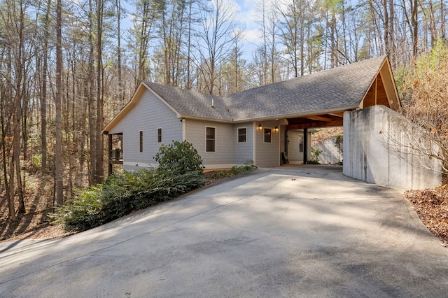 view of front of home featuring driveway, an attached carport, and roof with shingles