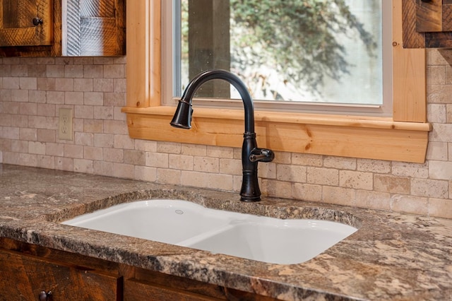 interior details with tasteful backsplash, dark countertops, and a sink