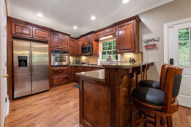 615 Navaho Way, Ellijay, GA 30540 - kitchen with appliances with stainless steel finishes, a breakfast bar area, a peninsula, a sink, and light wood-style floors