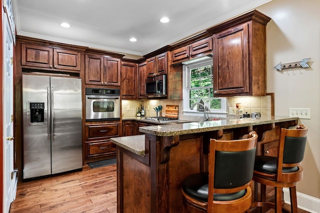 615 Navaho Way, Ellijay, GA 30540 - kitchen with stainless steel appliances, light wood-type flooring, a peninsula, a breakfast bar area, and crown molding