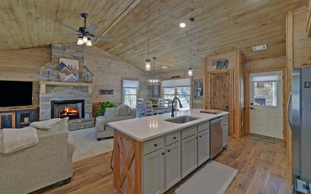 kitchen with stainless steel appliances, wood walls, wooden ceiling, and a sink