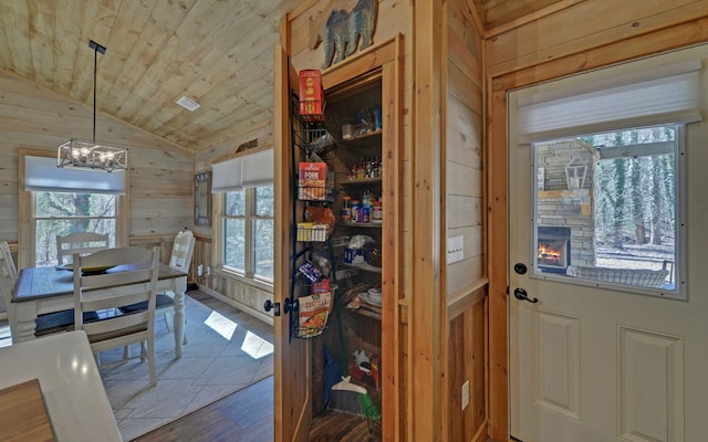 dining room featuring lofted ceiling, an inviting chandelier, wooden walls, wood finished floors, and wooden ceiling