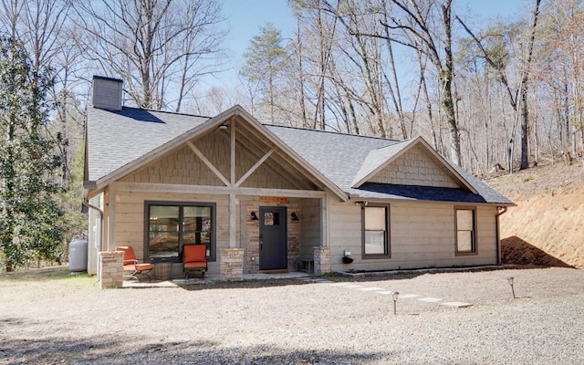 craftsman house featuring a chimney and roof with shingles