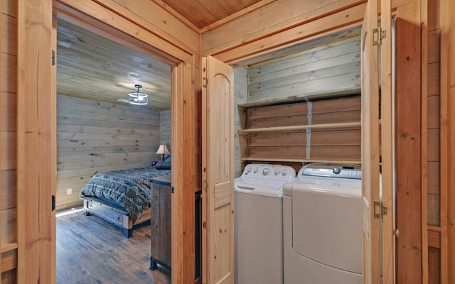 clothes washing area featuring wood ceiling, wooden walls, separate washer and dryer, and wood finished floors
