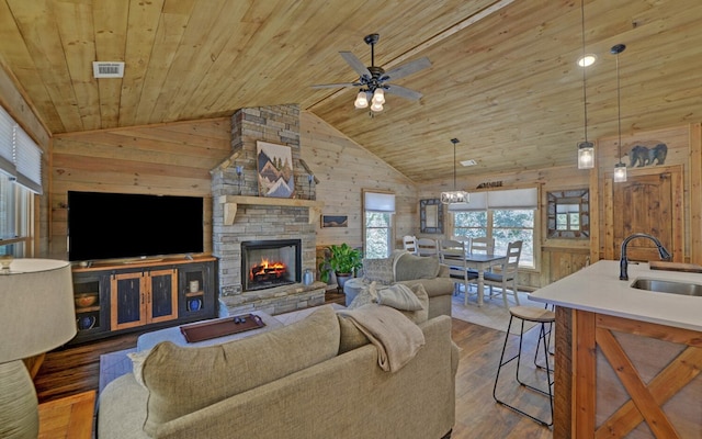 living area with wooden ceiling, wood walls, a stone fireplace, and wood finished floors