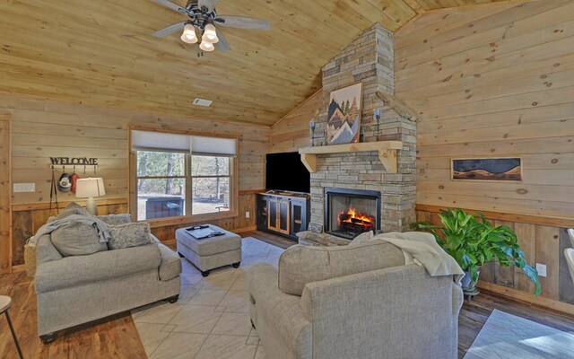 living area with wooden ceiling, wooden walls, visible vents, and a stone fireplace