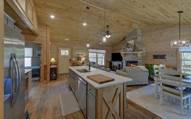 kitchen with wooden ceiling, wood walls, wood finished floors, a sink, and appliances with stainless steel finishes
