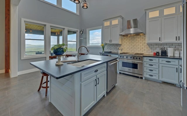 433 Hawkeye Trl, Marble, NC 28905 - kitchen featuring wall chimney range hood, tasteful backsplash, a sink, appliances with stainless steel finishes, and an island with sink
