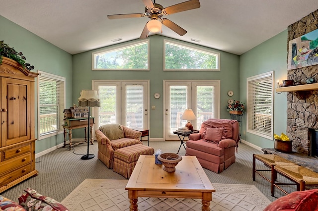 living room with ceiling fan, a healthy amount of sunlight, light colored carpet, and a stone fireplace