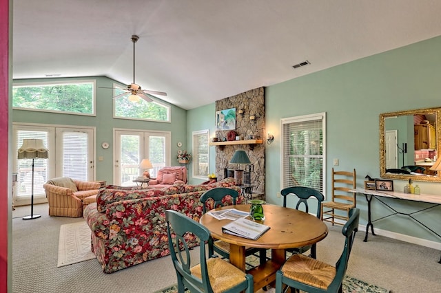 carpeted dining area with a wood stove, ceiling fan, and vaulted ceiling