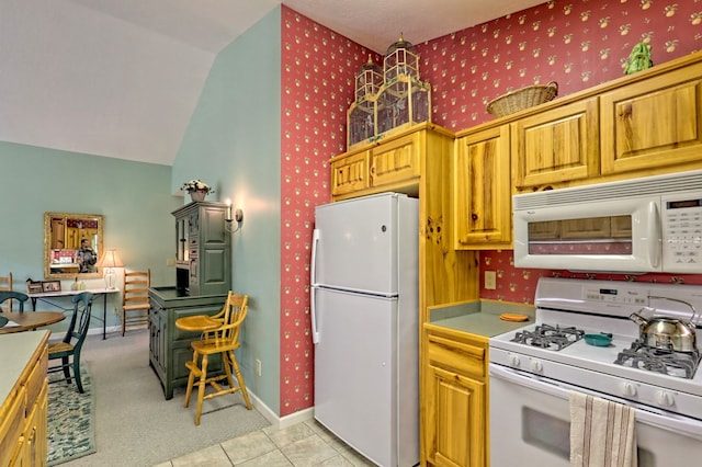 kitchen featuring lofted ceiling, white appliances, and light tile patterned floors