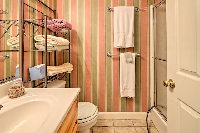 bathroom with tile patterned flooring, vanity, a shower with shower door, and toilet