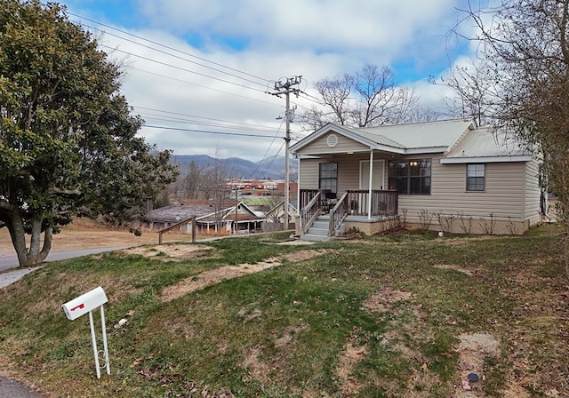 view of front of property with a mountain view, covered porch, and a front yard