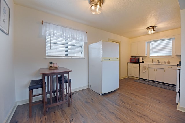 kitchen featuring dark hardwood / wood-style floors, white fridge, a textured ceiling, white cabinets, and range