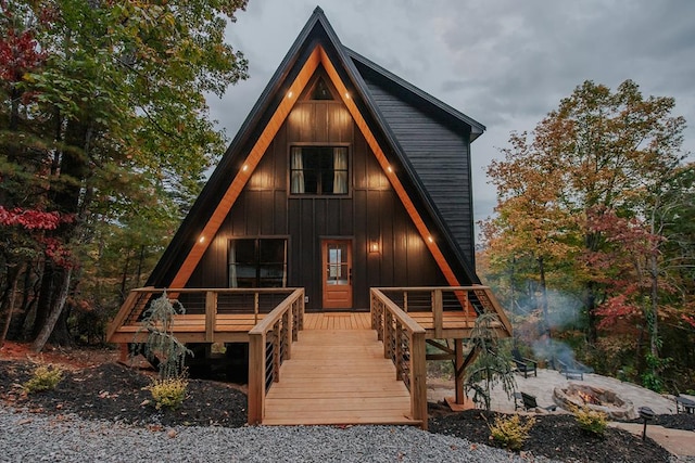 rear view of house featuring a fire pit and a wooden deck