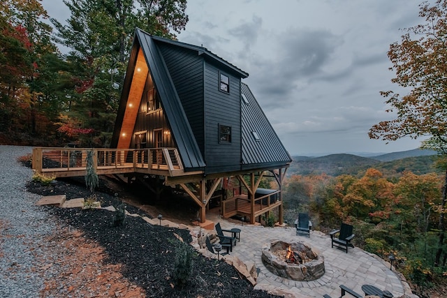 rear view of property with an outdoor fire pit, a deck with mountain view, and a patio area