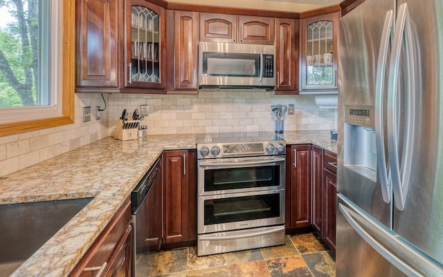 kitchen with light stone countertops, decorative backsplash, sink, and stainless steel appliances