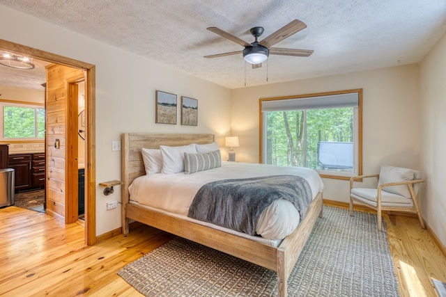 bedroom featuring ceiling fan, light hardwood / wood-style floors, and a textured ceiling