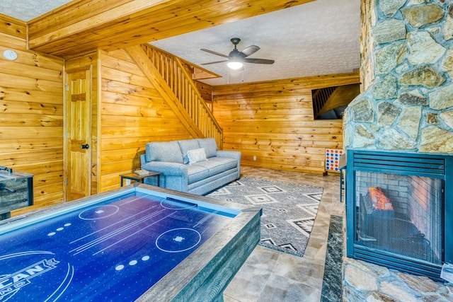 unfurnished living room featuring a textured ceiling, ceiling fan, and wood walls