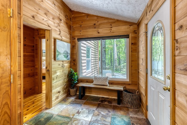 mudroom with a textured ceiling, lofted ceiling, and wood walls