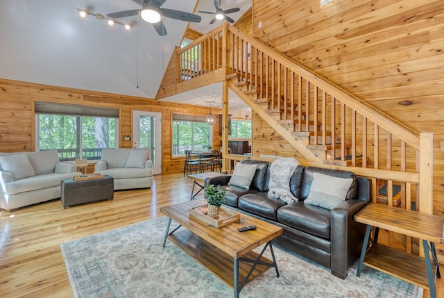 living room featuring wood walls, light hardwood / wood-style flooring, and high vaulted ceiling