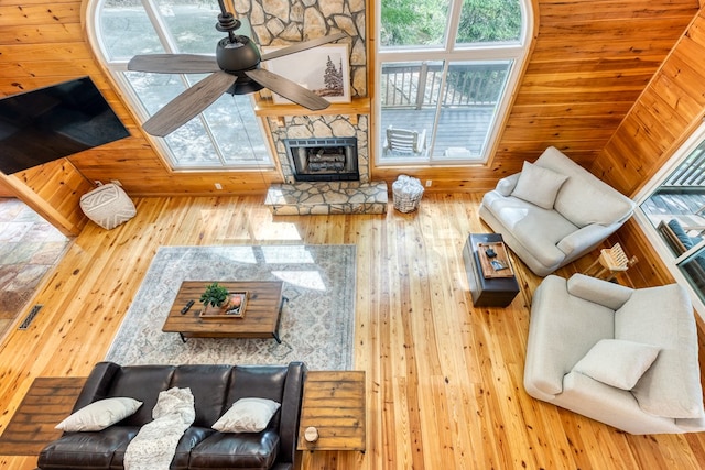 living room with a fireplace, ceiling fan, and wooden walls