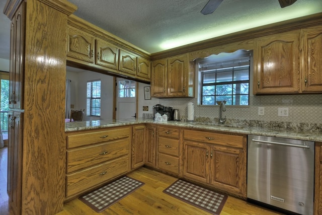 kitchen with brown cabinets, light wood-style floors, dishwasher, and a sink