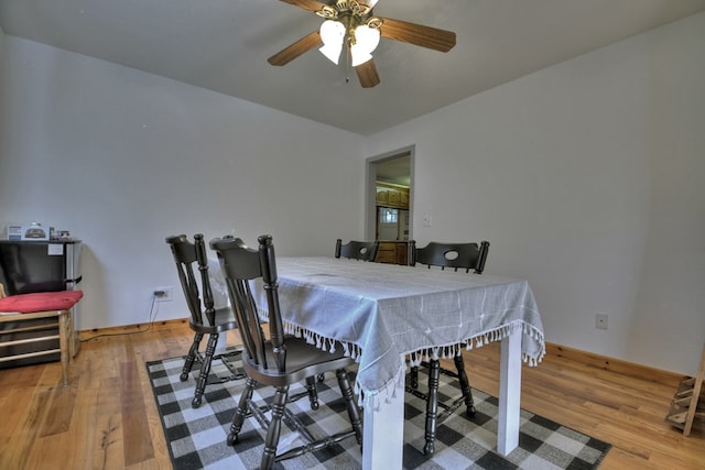 dining area featuring wood finished floors, a ceiling fan, and baseboards
