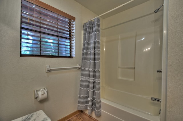 full bath featuring a textured wall and shower / bath combo with shower curtain