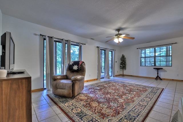 living area with a ceiling fan, baseboards, and light tile patterned floors