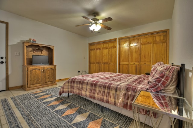bedroom featuring multiple closets, baseboards, light tile patterned floors, and a ceiling fan