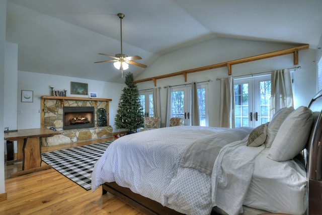 bedroom featuring vaulted ceiling, a stone fireplace, wood finished floors, french doors, and access to outside