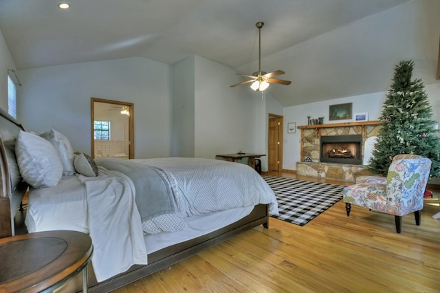 bedroom with vaulted ceiling, wood finished floors, a fireplace, and ceiling fan
