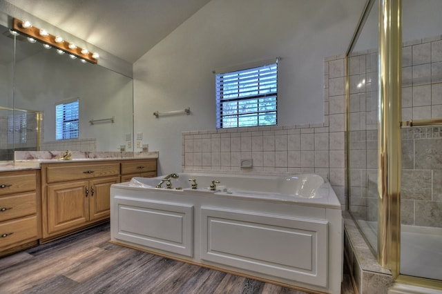 full bathroom featuring a tile shower, vaulted ceiling, wood finished floors, a garden tub, and vanity