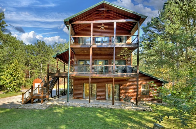 rear view of house with log siding, a patio area, a balcony, stairway, and a yard