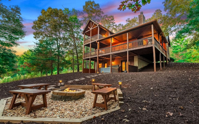 back house at dusk with a fire pit and a deck