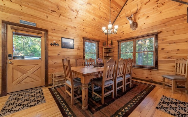 dining room featuring a chandelier, light hardwood / wood-style floors, wood ceiling, and wood walls