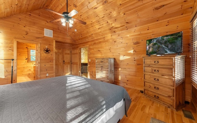 bedroom with wooden walls, ceiling fan, and light wood-type flooring