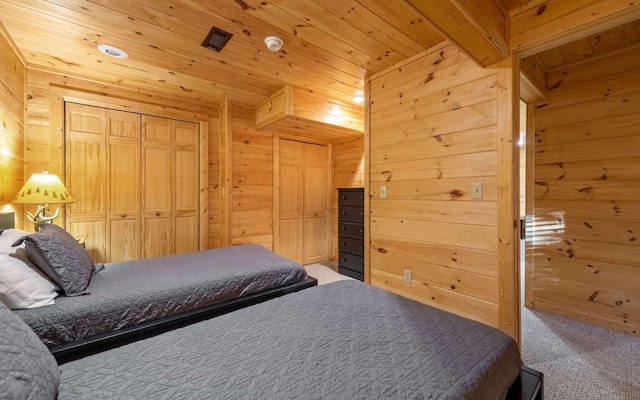 bedroom featuring carpet flooring, beam ceiling, wooden walls, and a closet