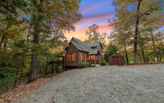 property exterior at dusk featuring a shed and a deck