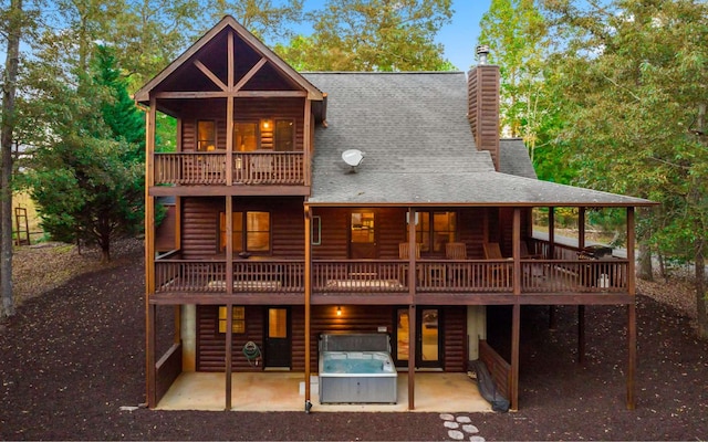 back of house featuring a deck, a patio, and a hot tub